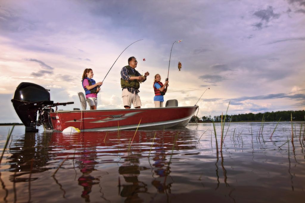 Image of a man fishing at sunset with two children. 