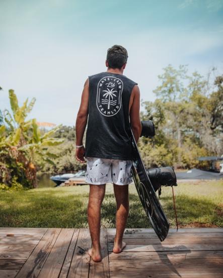 Image of a man from behind, holding a wakeboard. 