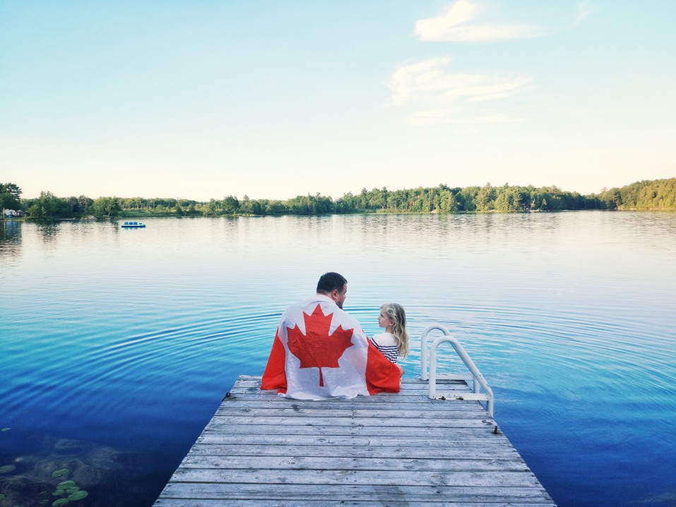 Father and daughter sitting on dock in Muskoka Ontario