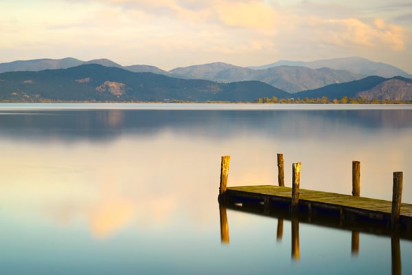 A dock on a chilly lake with mountains in the background.