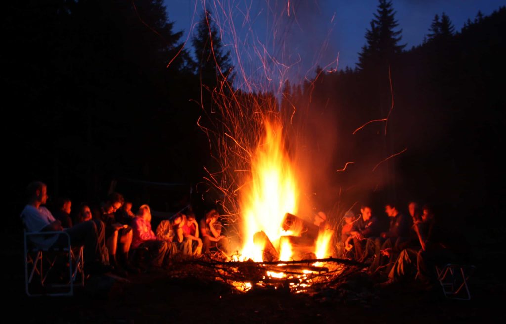 People around a campfire at night, cottage hacks concept.