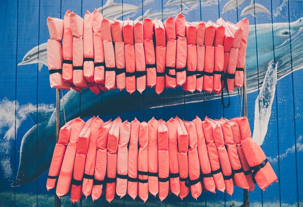 Two rows of life jackets hanging on a rack, New York State life jacket laws concept.