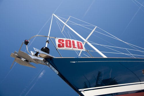 A "sold" sign on the front of a boat, buying your first boat concept.