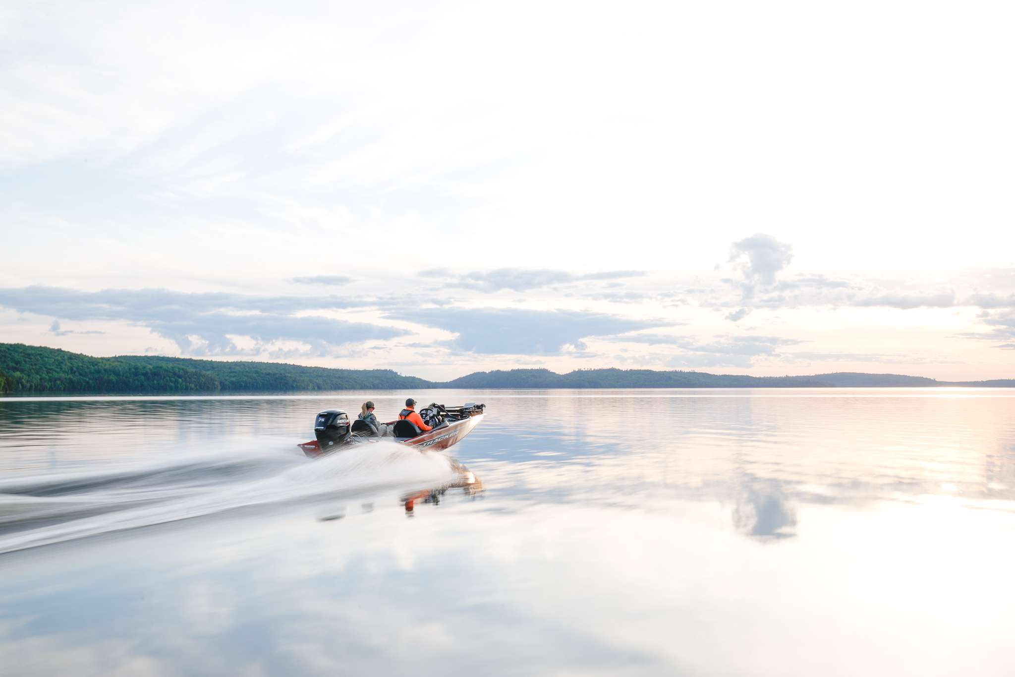 A fast-moving fishing boat with two people on board, know Massachusetts boating laws concept.