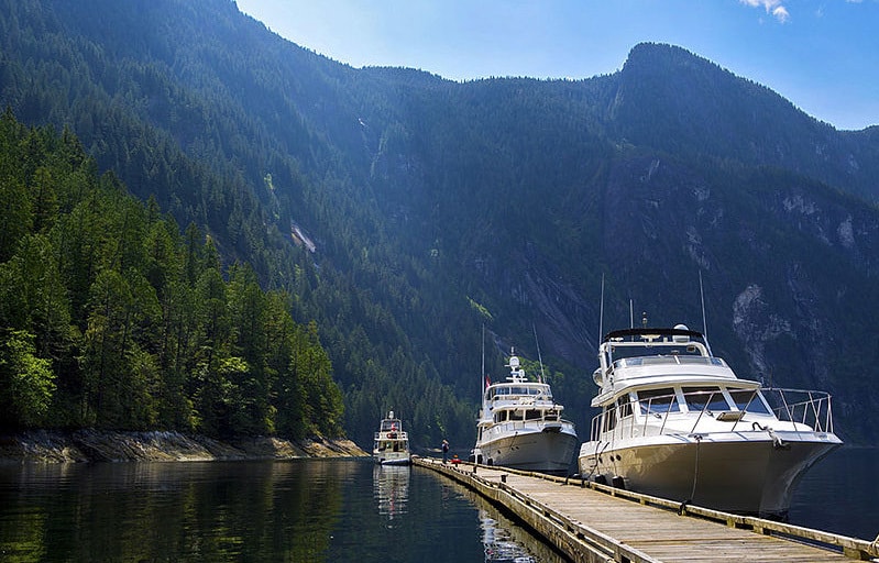 Yachts moored at a dock with mountains in the background, used boat concept.
