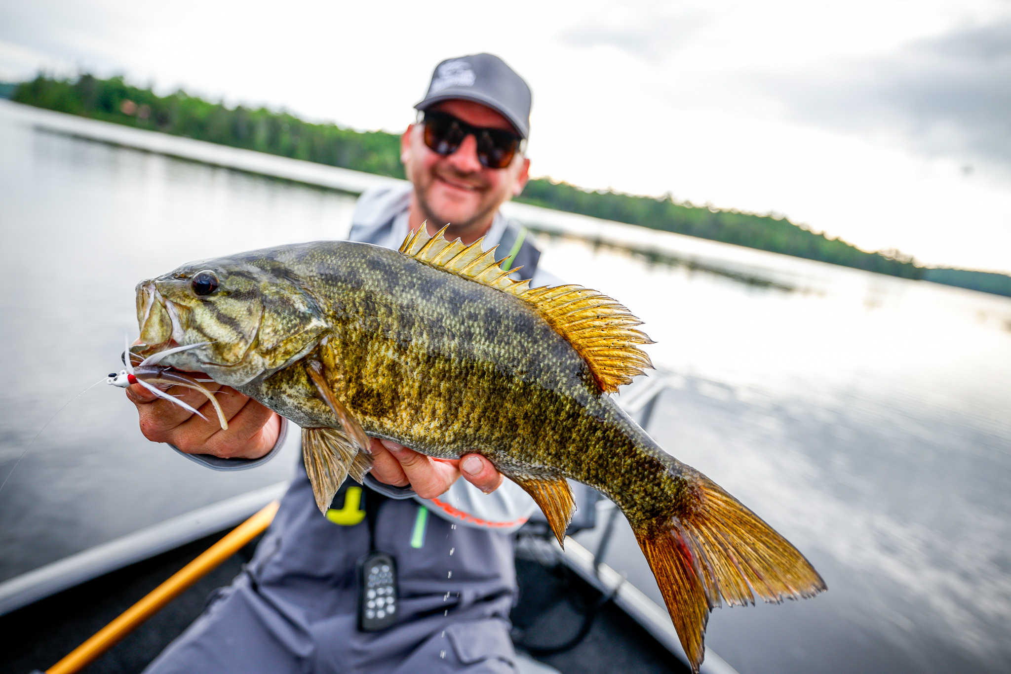 A man holds a fish while on a boat, fishing in Kansas concept.