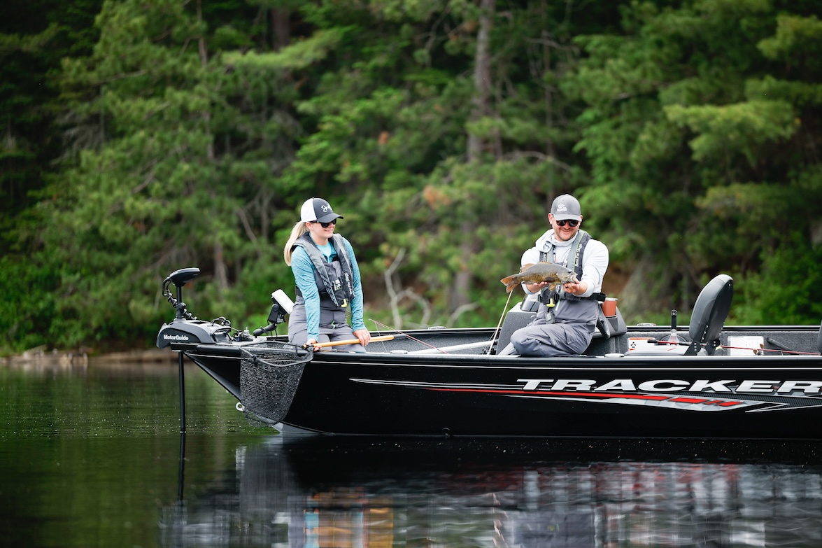Two people on a fishing boat, one of them holding a fish, using Fishbrain to find fish concept.