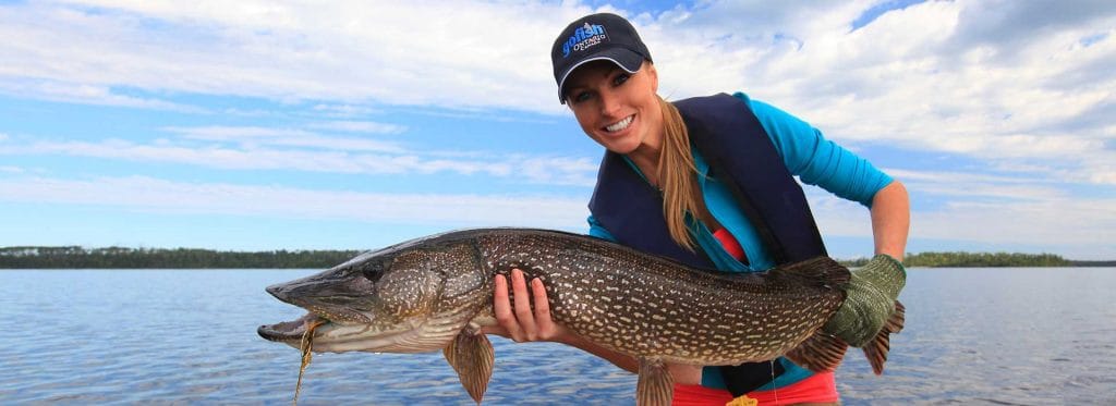 A woman holds up a freshly-caught large fish, fall fishing concept. 