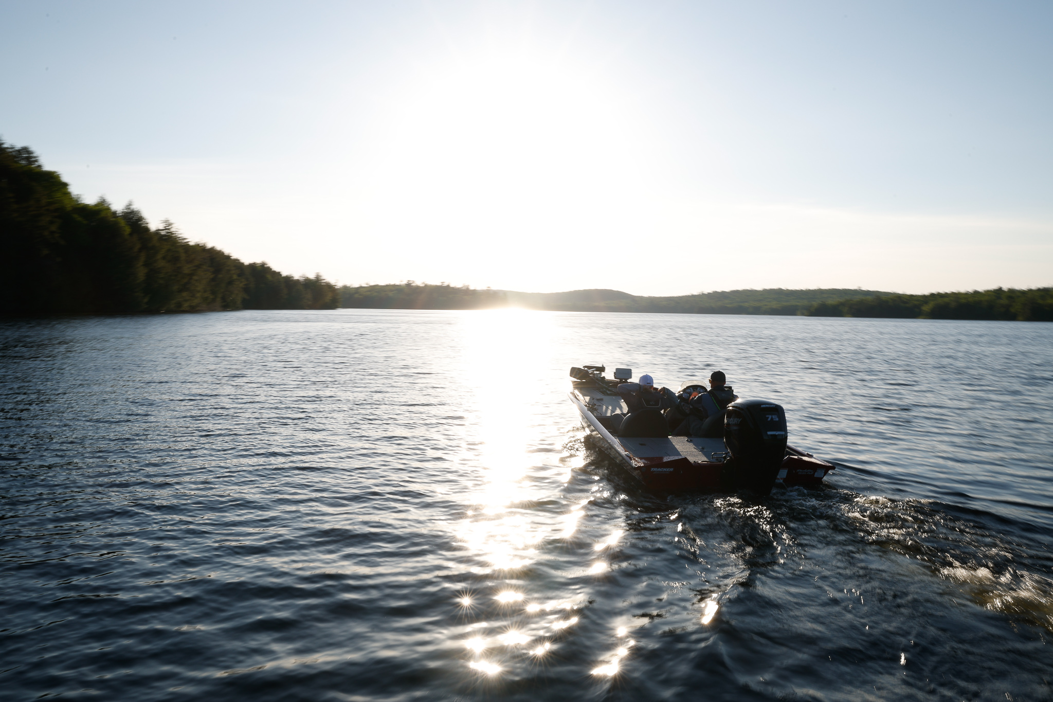 A boat moves calmly on a lake and sunset.