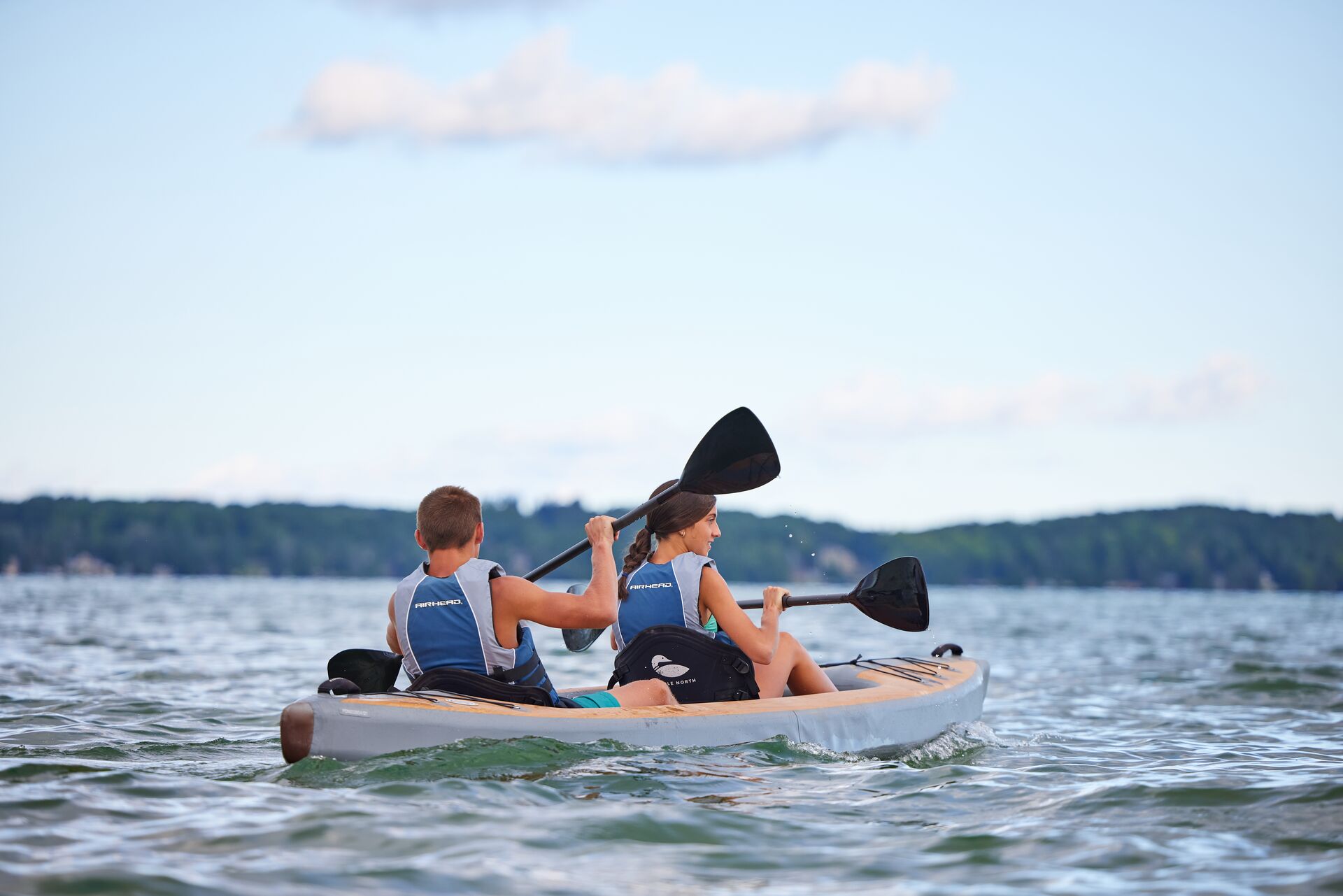 A boy and girl paddling a kayak on the water, boating in Washington concept.