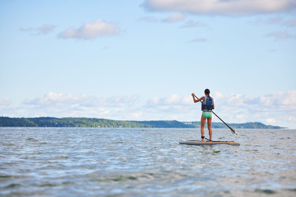 A girl on a paddle board on a lake, best lakes in Manitoba concept.