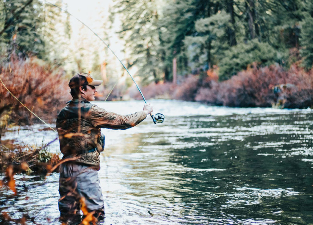 A man fly fishing in the water, best lakes in Manitoba for boating and fishing.
