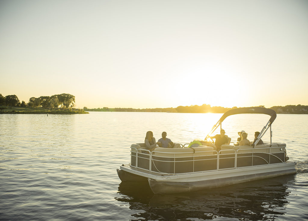 People enjoying a pontoon boat on a calm lake.