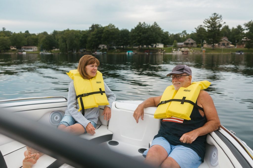 A man and woman wearing yellow lifejackets enjoy a boat, boat registration in Ohio concept.