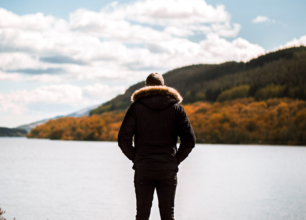 A person wearing a coat looking out over the water, boating off-season activities concept. 