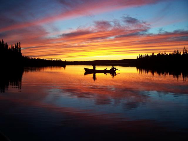People in a fishing boat while fishing at sunset