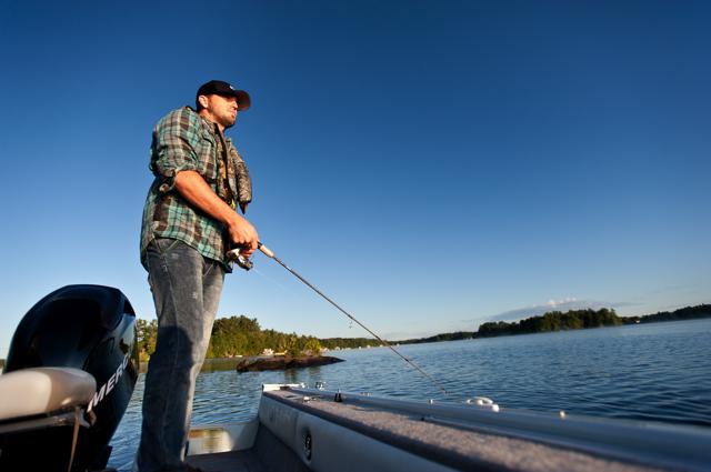 An angler on a boat with a rod and reel in the water, fall fishing concept.
