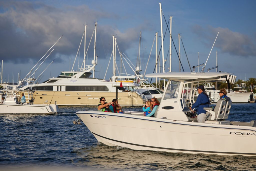 People on a boat driving in front of boats docked at a marina, marinas in Virginia concept.