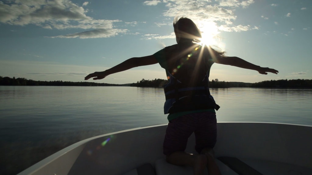 Silhouette of a person at the front of a boat.