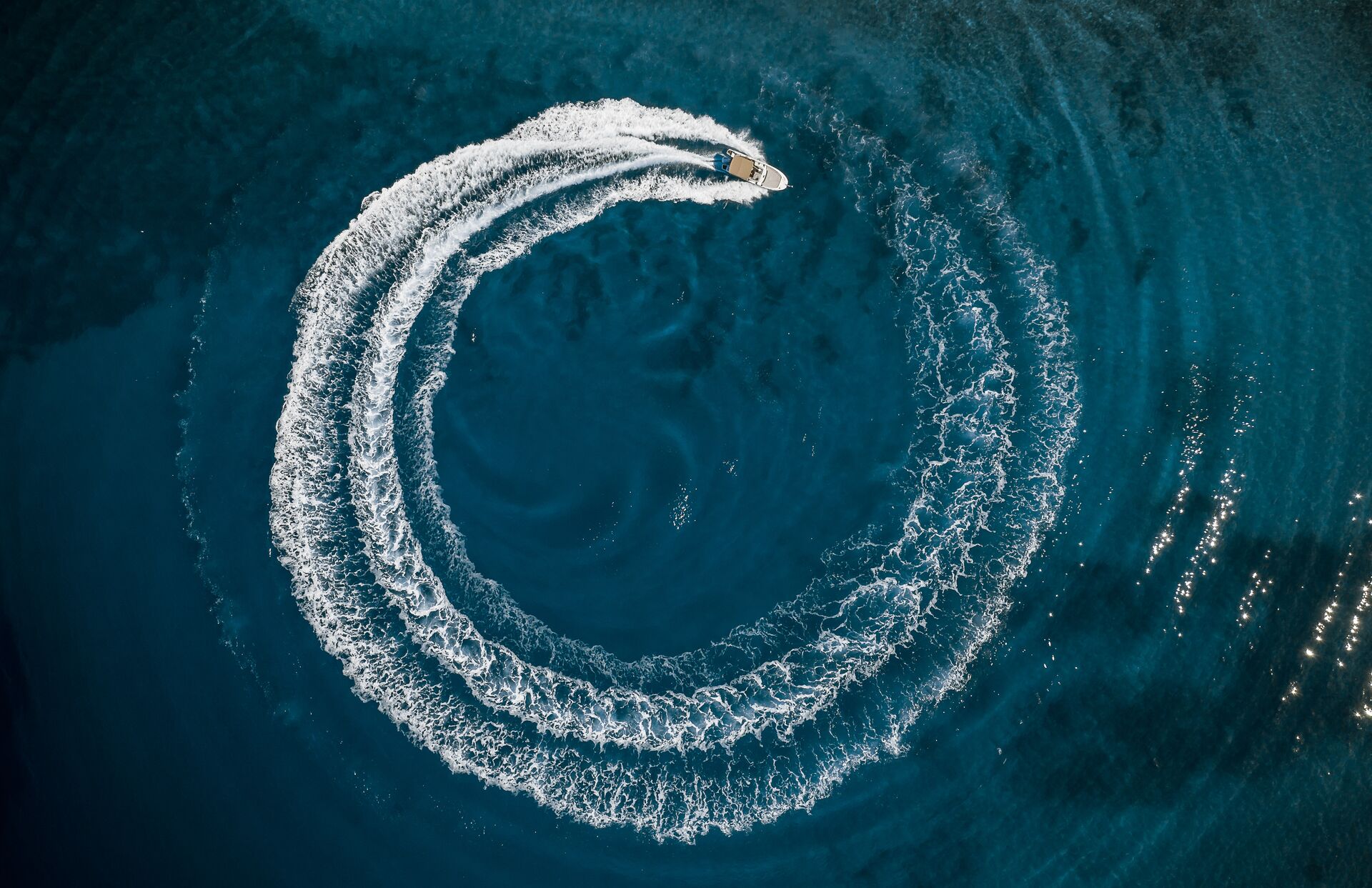 Aerial view of a boat driving in a circle in the water. 