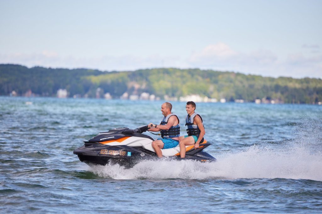 Two guys on a jetski, wearing life jackets concept.