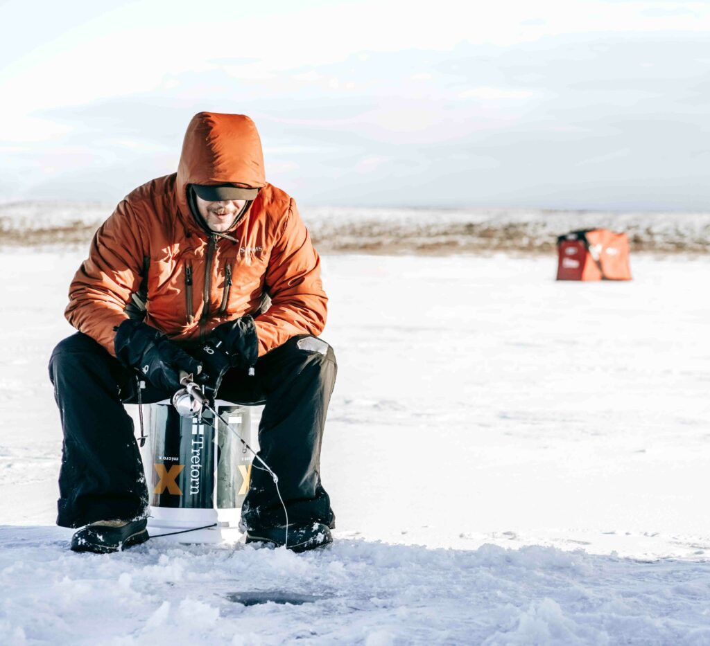 Man sitting at ice fishing hole, boating off-season activities concept. 