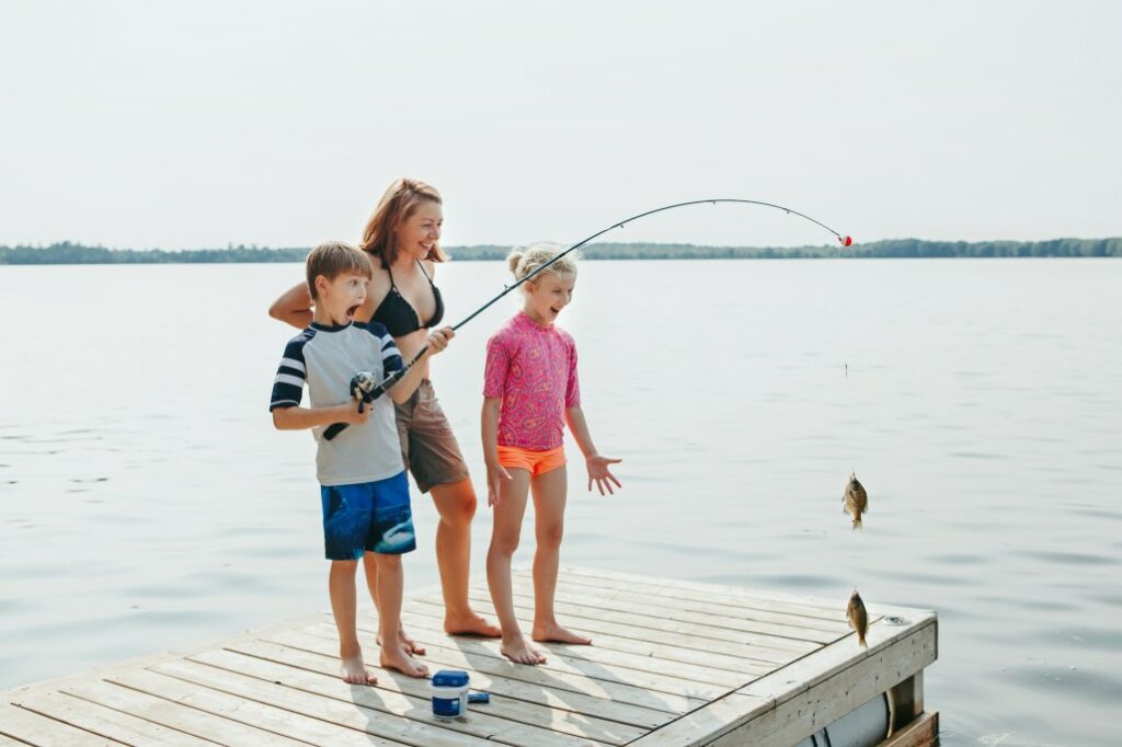 A woman with two children fishing from a dock.
