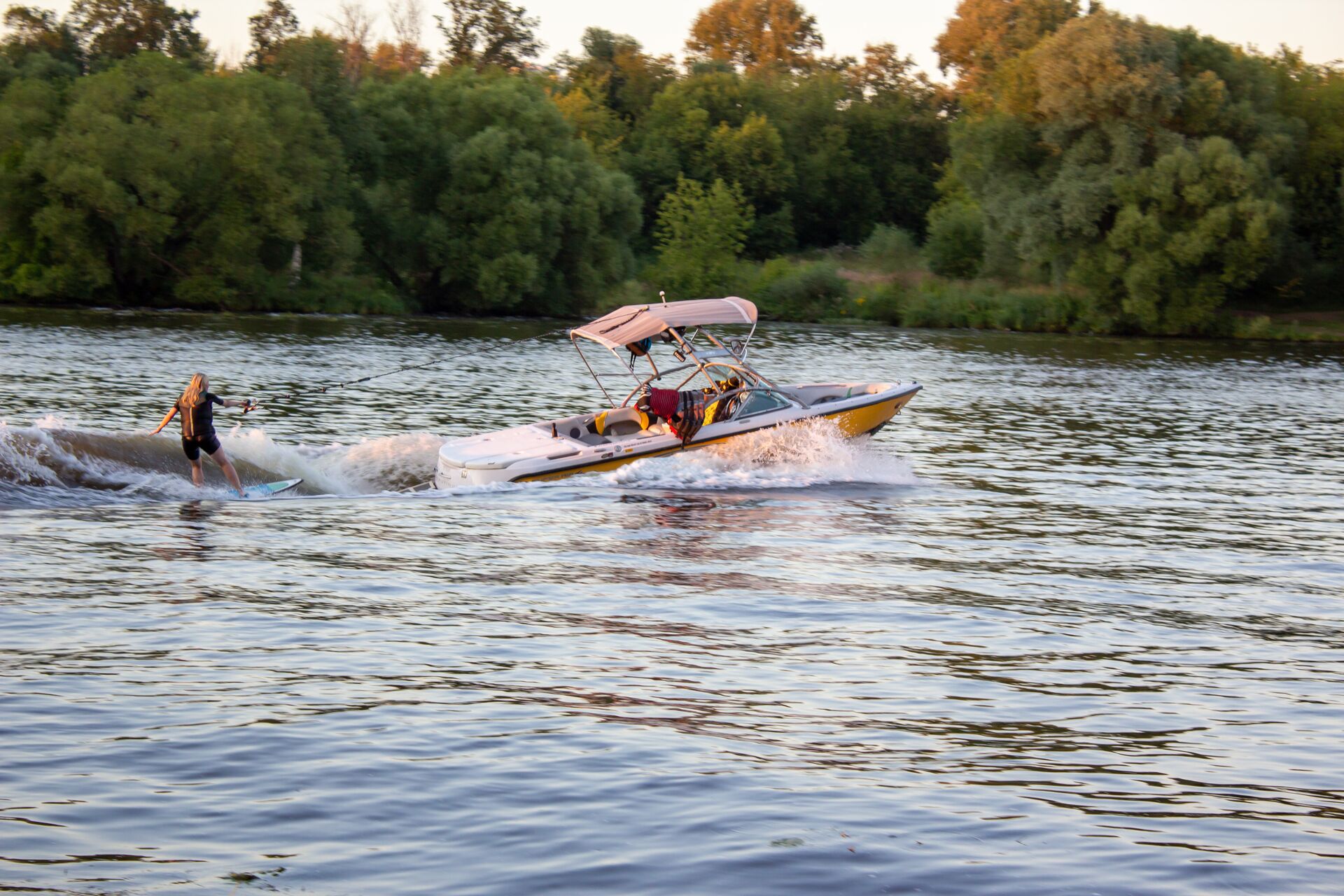 Side view of a person on a waterski behind a boat on a lake. 