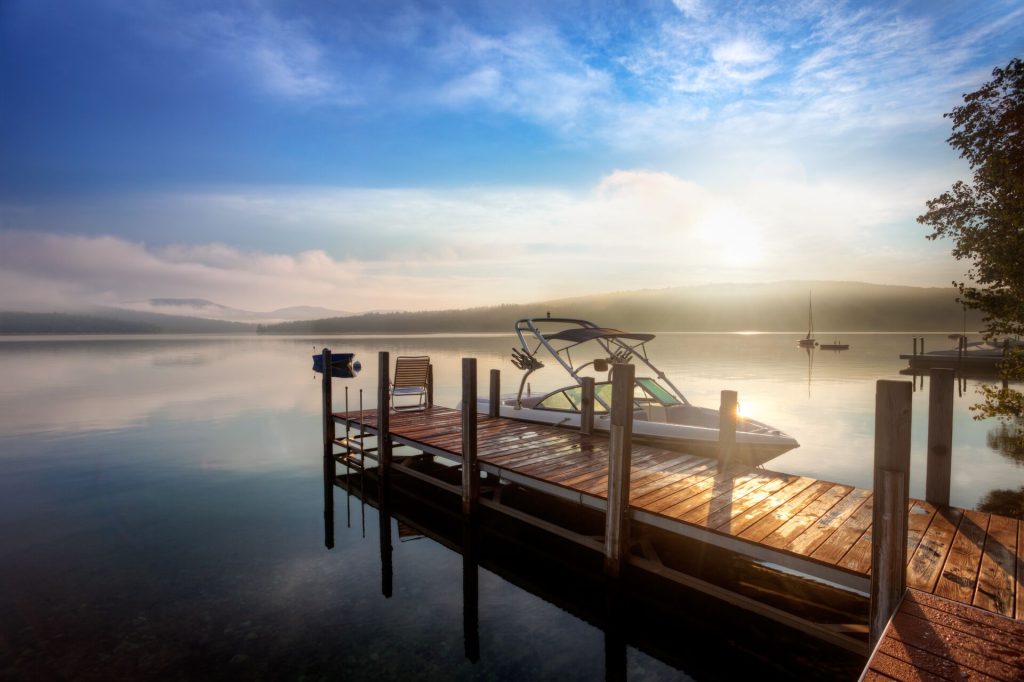 A boat moored at a dock on a calm lake.