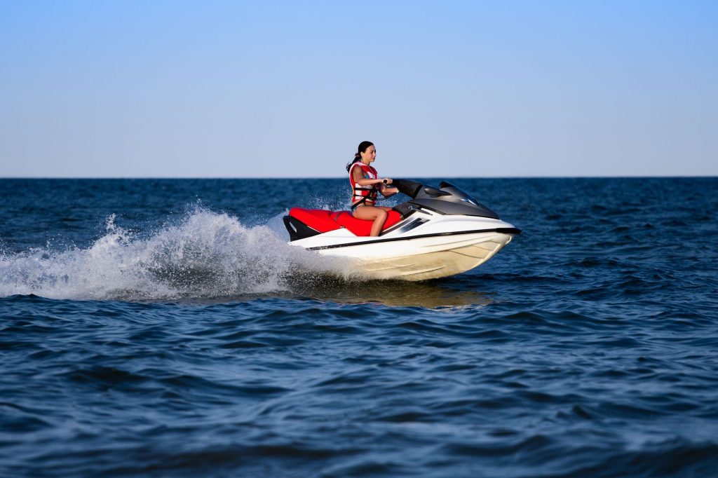 A girl driving a personal watercraft while wearing a lifejacket, PWC safety concept.