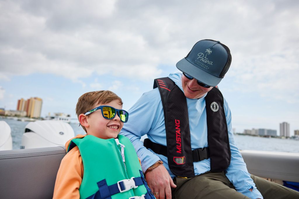 A man smiles at a smiling boy on a boat.