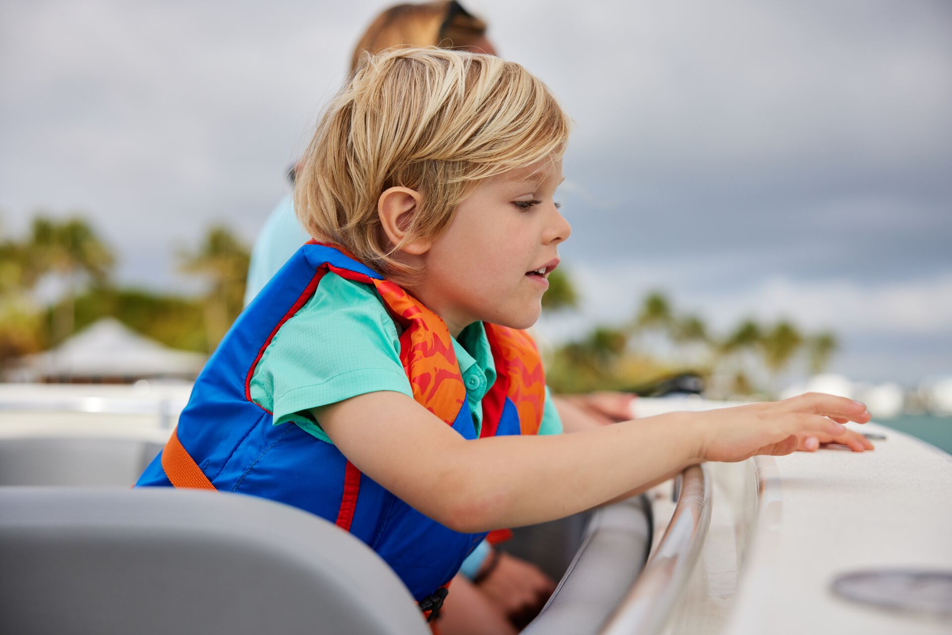 A child looks over the side of a boat.