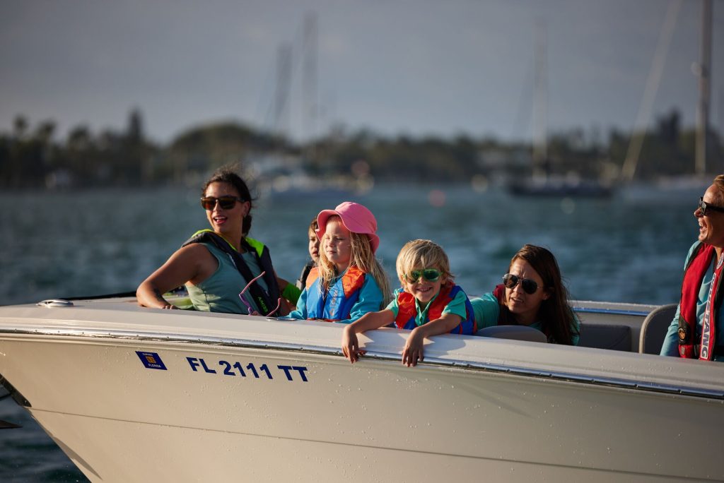 Women and kids wearing lifejackets at the front of a boat, safe boating concept.