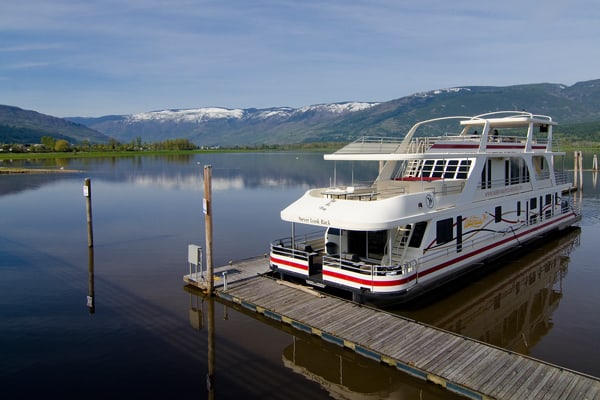 A boat at the dock on a lake with mountains in the background. 
