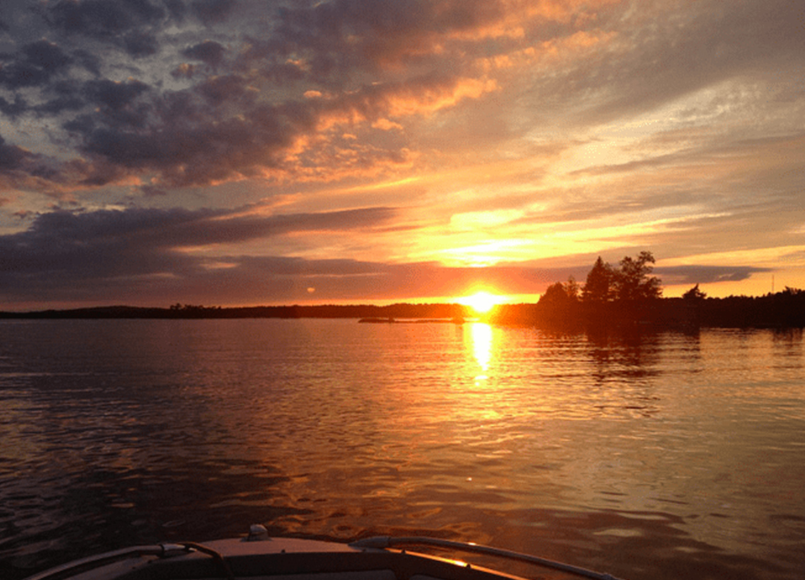 Sunset on a lake looking over the front of a boat, boating in Canada concept. 