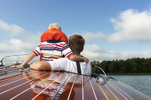 A man with a child on a boat wearing life jackets.