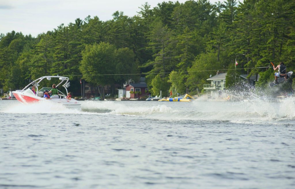 A boat pulling a wakeboarder behind it, boating in Canada concept. 