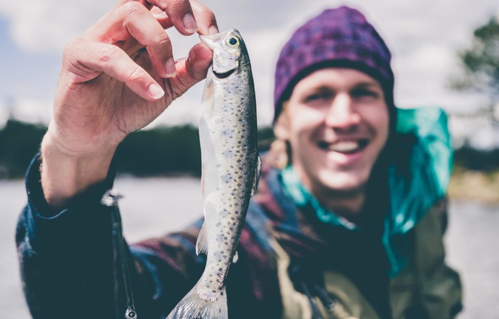 A man holding a fish, get your boating license and go fishing.