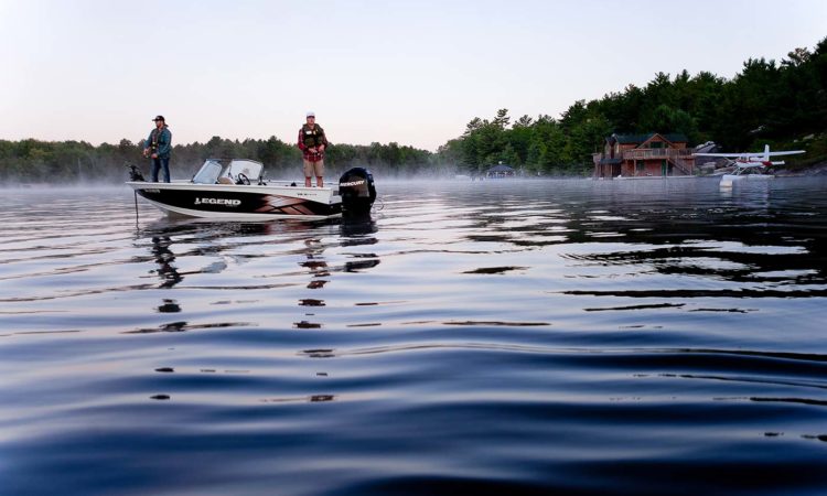 Two fishermen in boat with pontoon plane in background