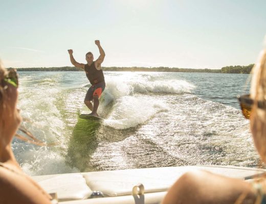 Dude wake surfing with hands in the air