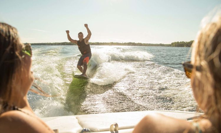 Dude wake surfing with hands in the air