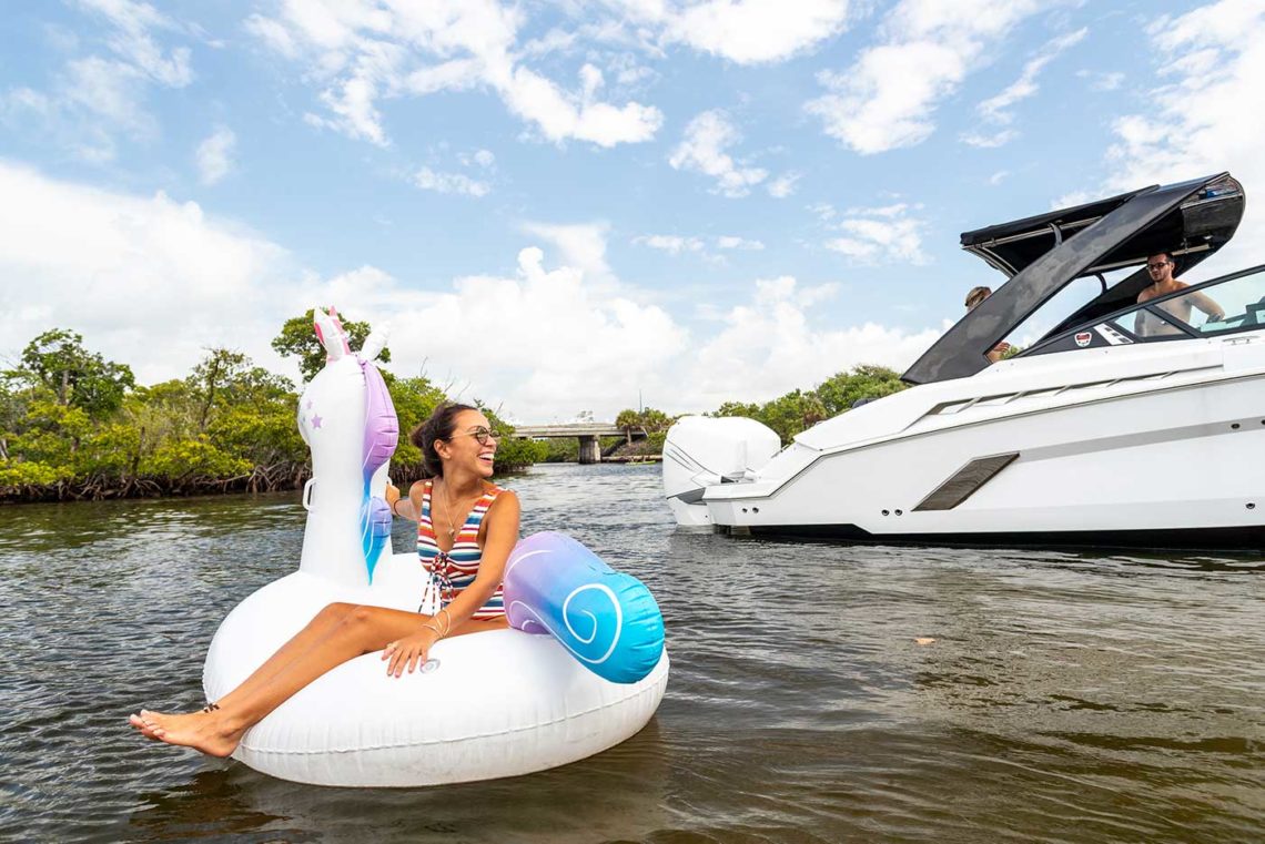 girl sitting on inflatable unicorn floating next to boat