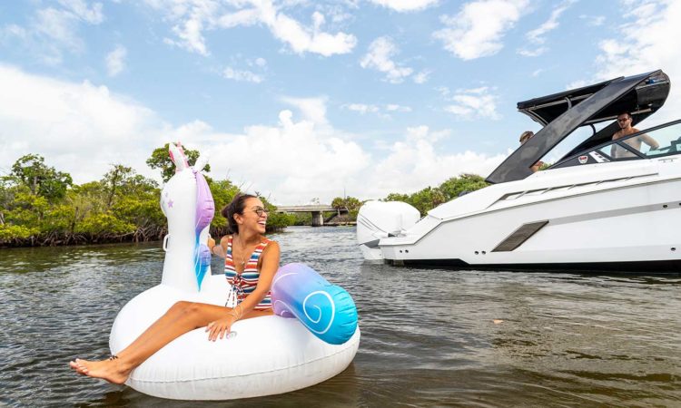 girl sitting on inflatable unicorn floating next to boat