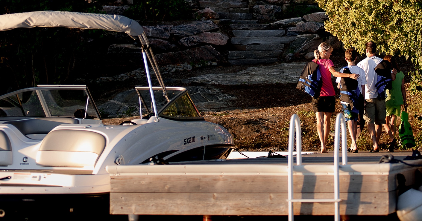 a family of boaters walks away from a pier with a docked boat tied up beside them