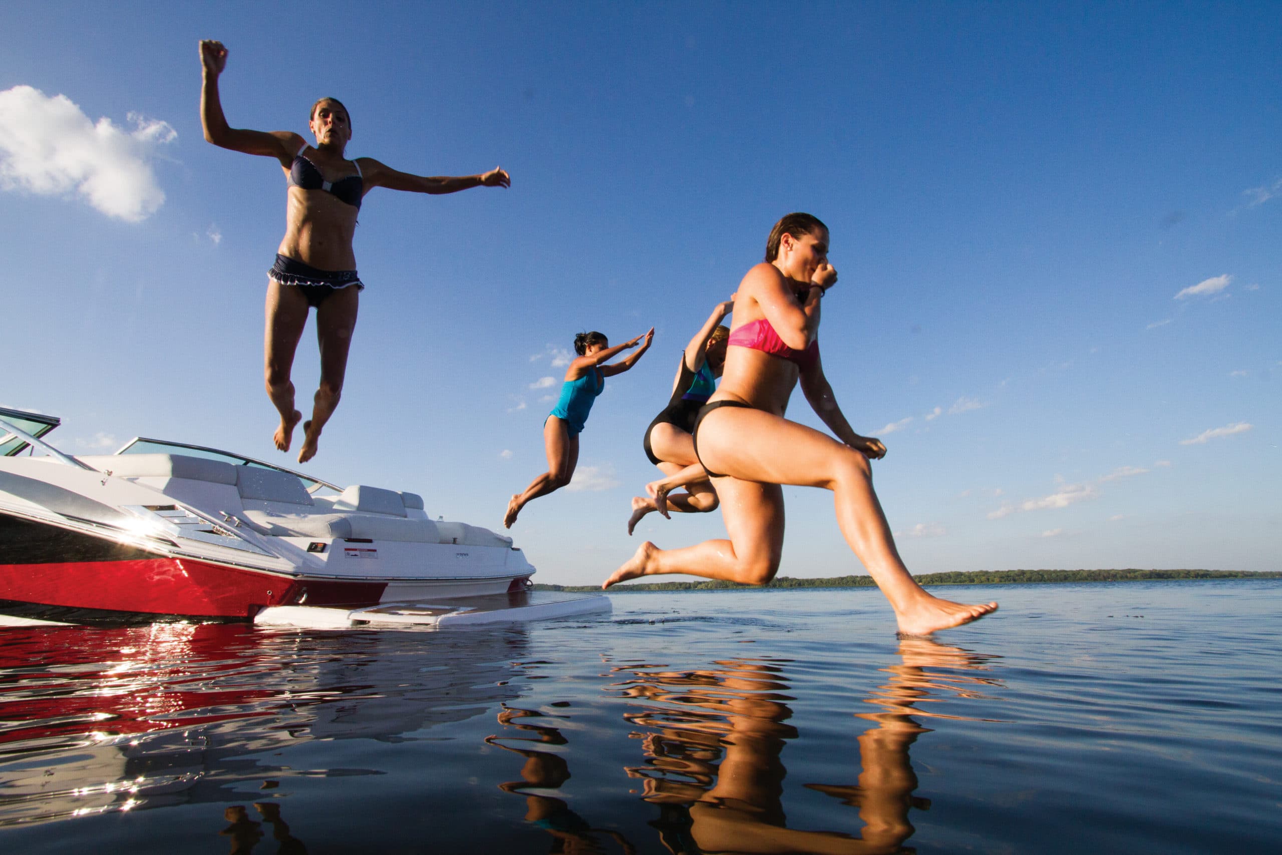 kids jumping into water from boat